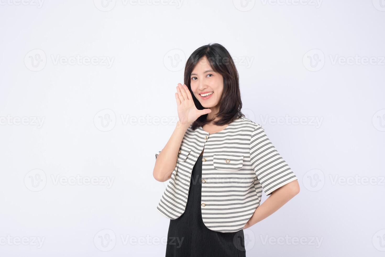 Southeast asian woman smiling and advertising with hand gesture wearing striped jacket and black dress on white background photo
