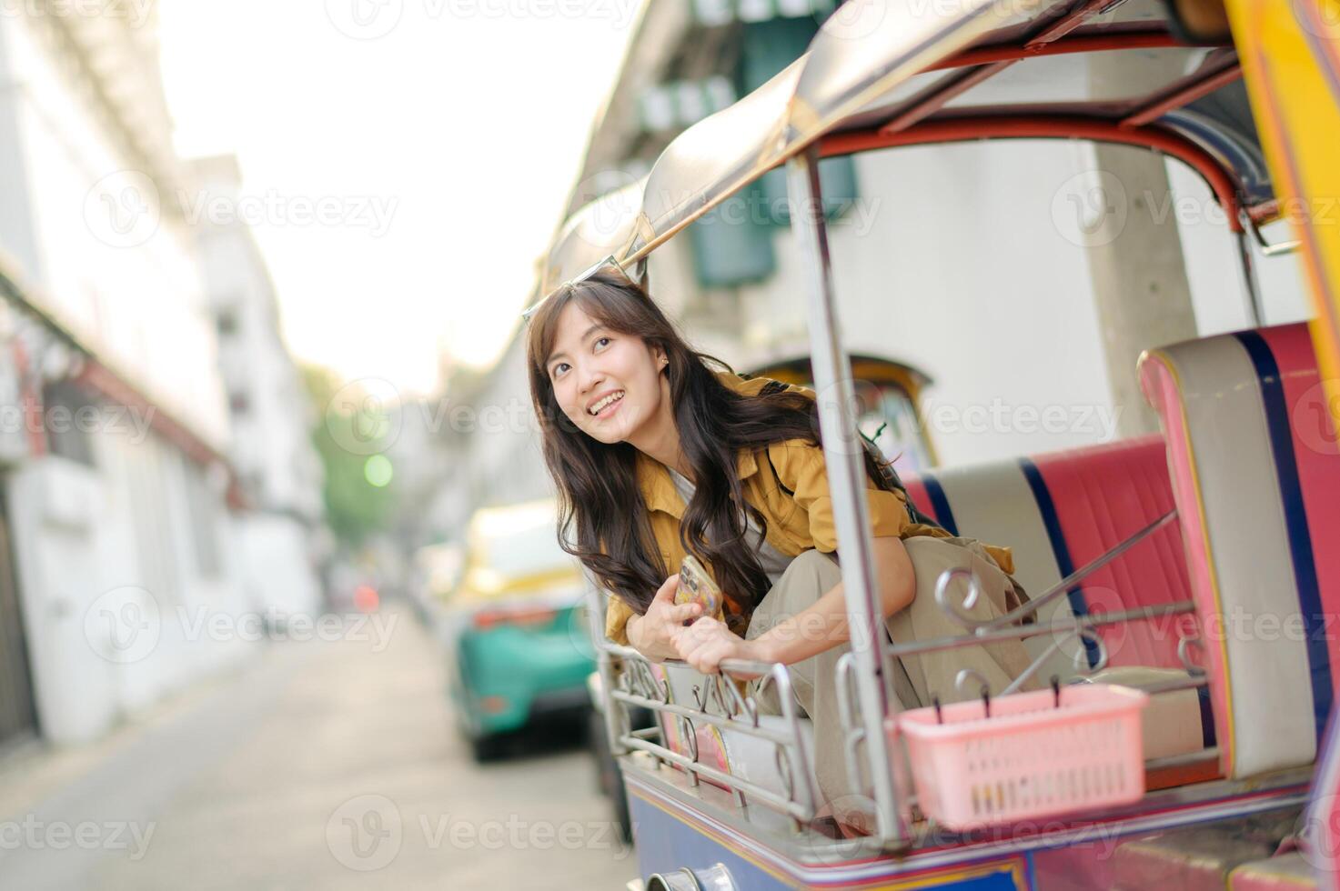 Southeast asian woman travel concept is captured as she happily leans out of colorful tuk tuk on city street enjoying her journey and vibrant urban atmosphere photo