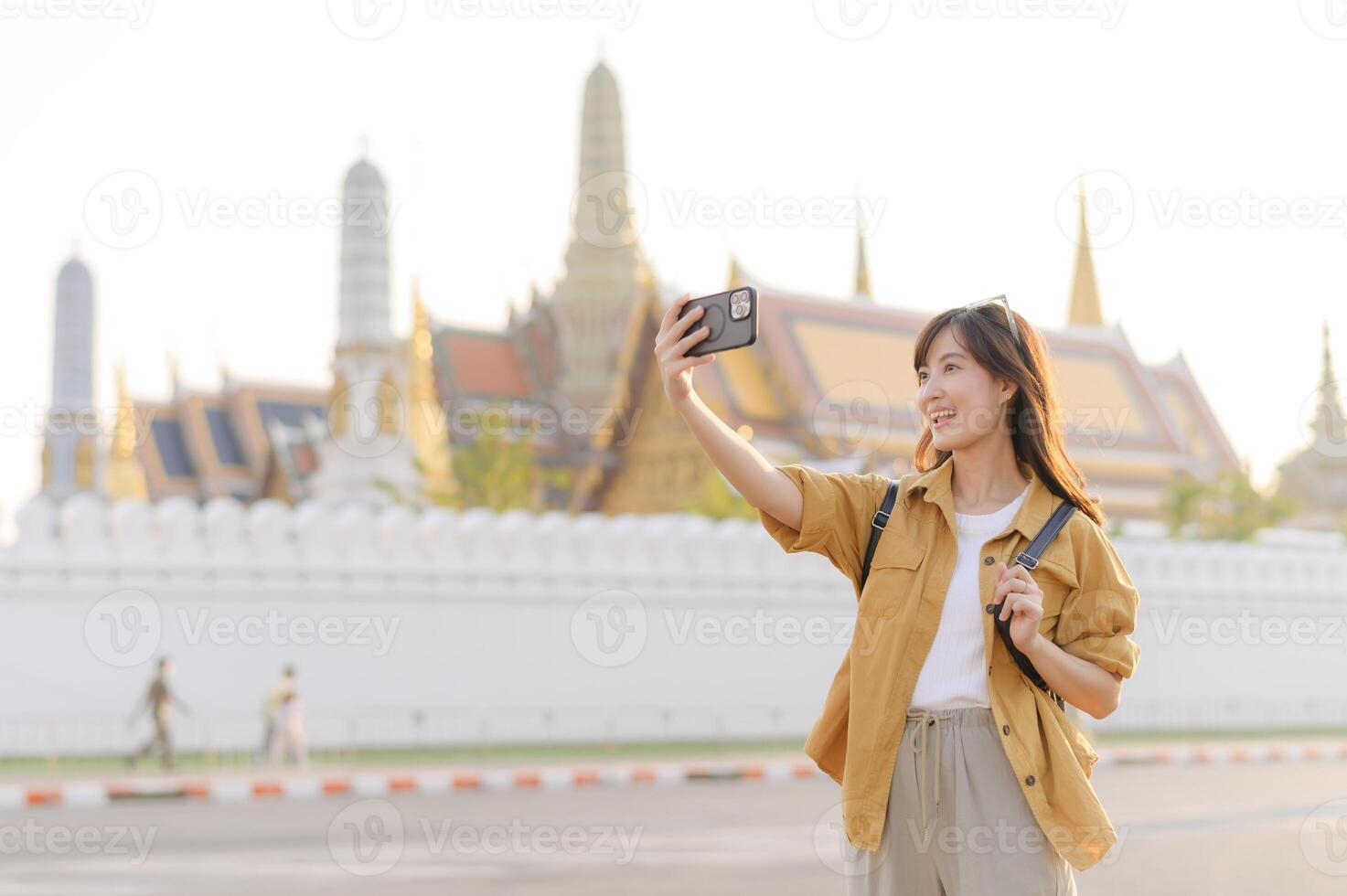 Southeast asian woman travel concept captures joyful woman taking selfie with historic temple background during her travel adventure in bright and warm atmosphere photo