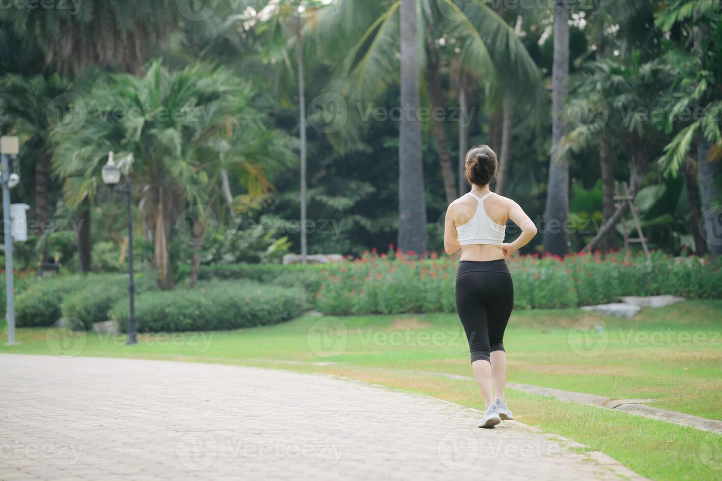 Southeast asian woman enjoying wellness and healthy lifestyle concept while doing exercise in park surrounded by green trees and nature, feeling relaxed and active outdoors photo