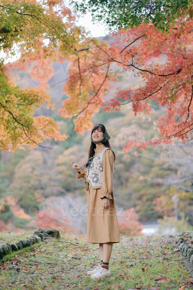 Southeast asian woman enjoys travel concept in autumn nature surrounded by colorful leaves and peaceful scenery expressing calm and joy in outdoor environment photo