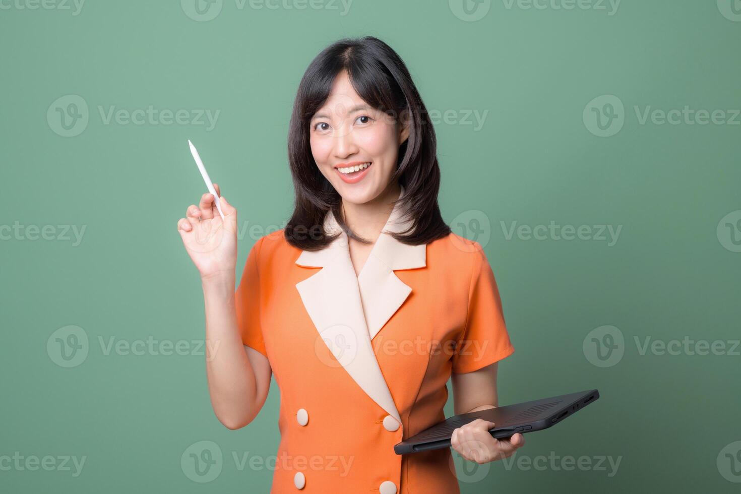 Southeast asian woman smiling confidently while using internet technology holding digital tablet and stylus pen against green background photo