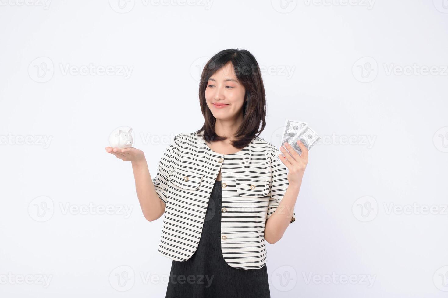 Southeast asian woman is shopping online happily while holding cash and piggy bank symbolizing saving money and smart financial choices in bright setting photo