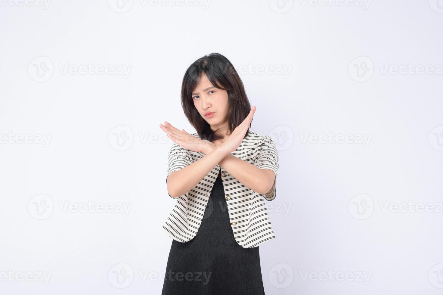 Southeast asian woman shows serious expression with crossed arms in gesture of refusal or advertising no sign in plain background photo