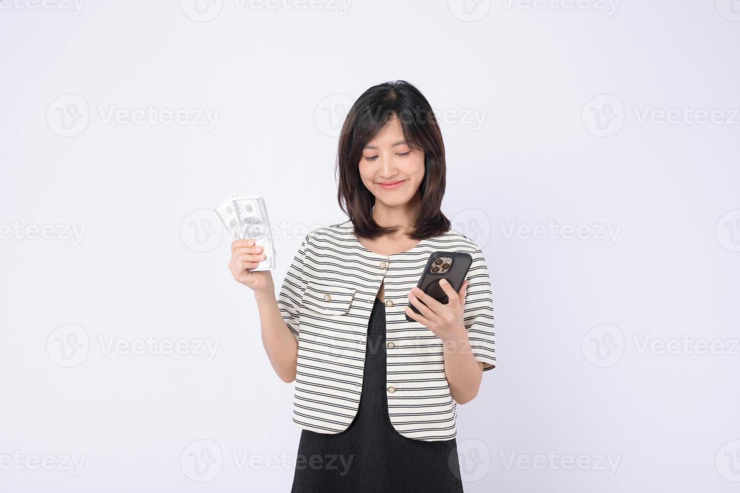 Southeast asian woman happily uses mobile phone application on internet while holding cash in her hand showing satisfaction and convenience in digital finance photo