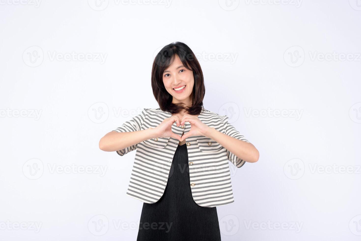Southeast asian woman smiling warmly and making heart shape with her hands for advertising and positive connection photo