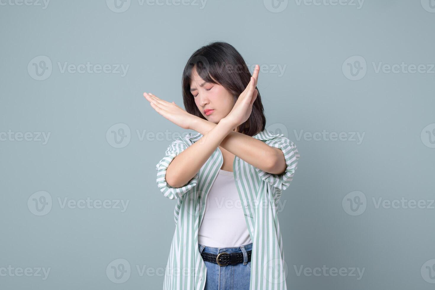Southeast asian woman shows stop gesture with crossed arms expressing refusal or no in creative way for small business owner in retail or online store startup industry photo