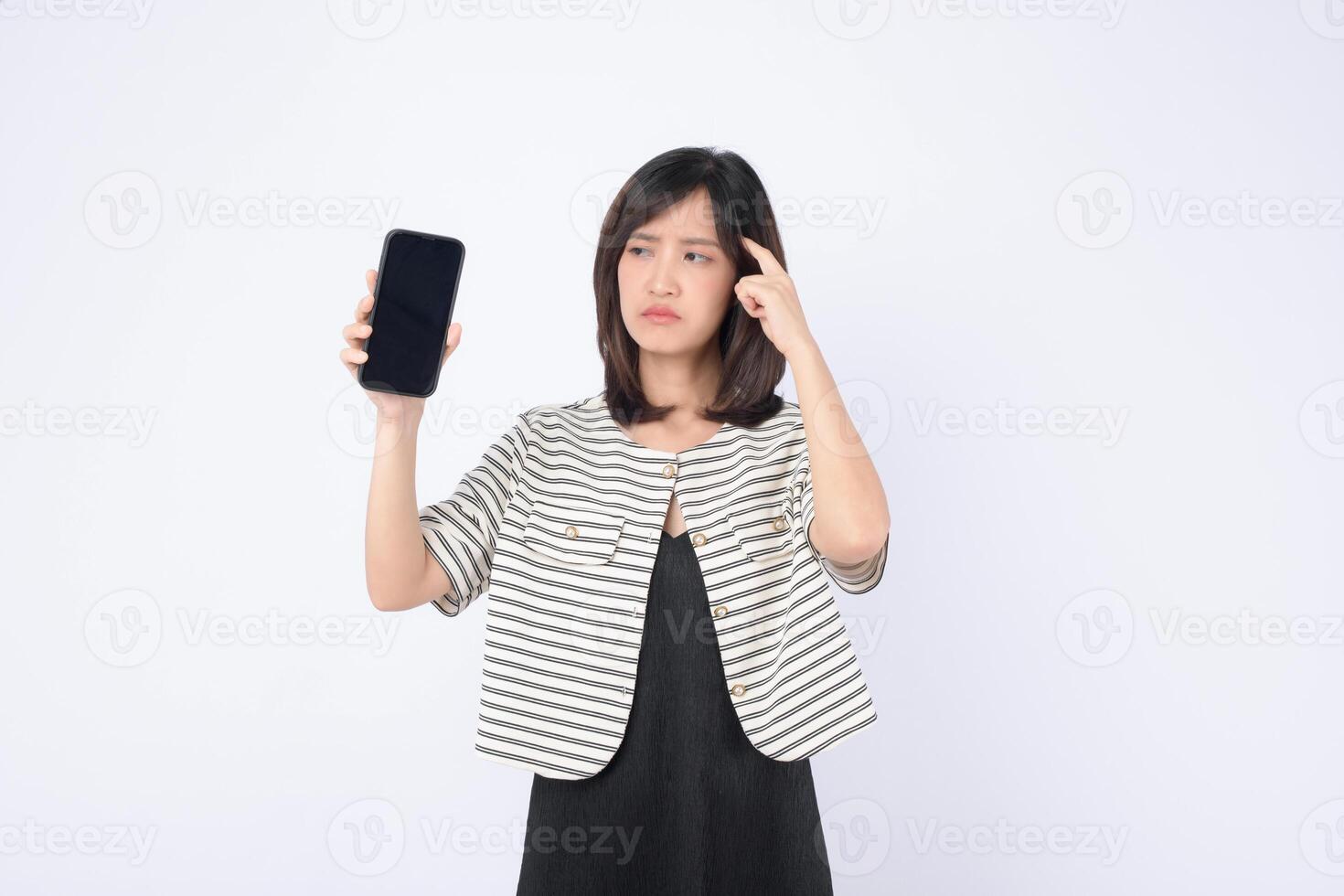 Southeast asian woman looks confused while holding mobile phone showing blank screen as she tries to use internet application on white background photo