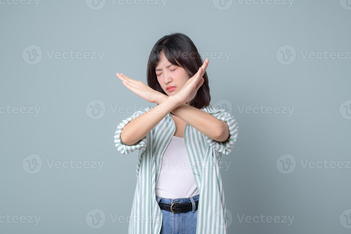 Southeast asian woman showing stop gesture with crossed arms and closed eyes expressing refusal or disapproval in creative way for small business owner or retail startup in online store industry photo