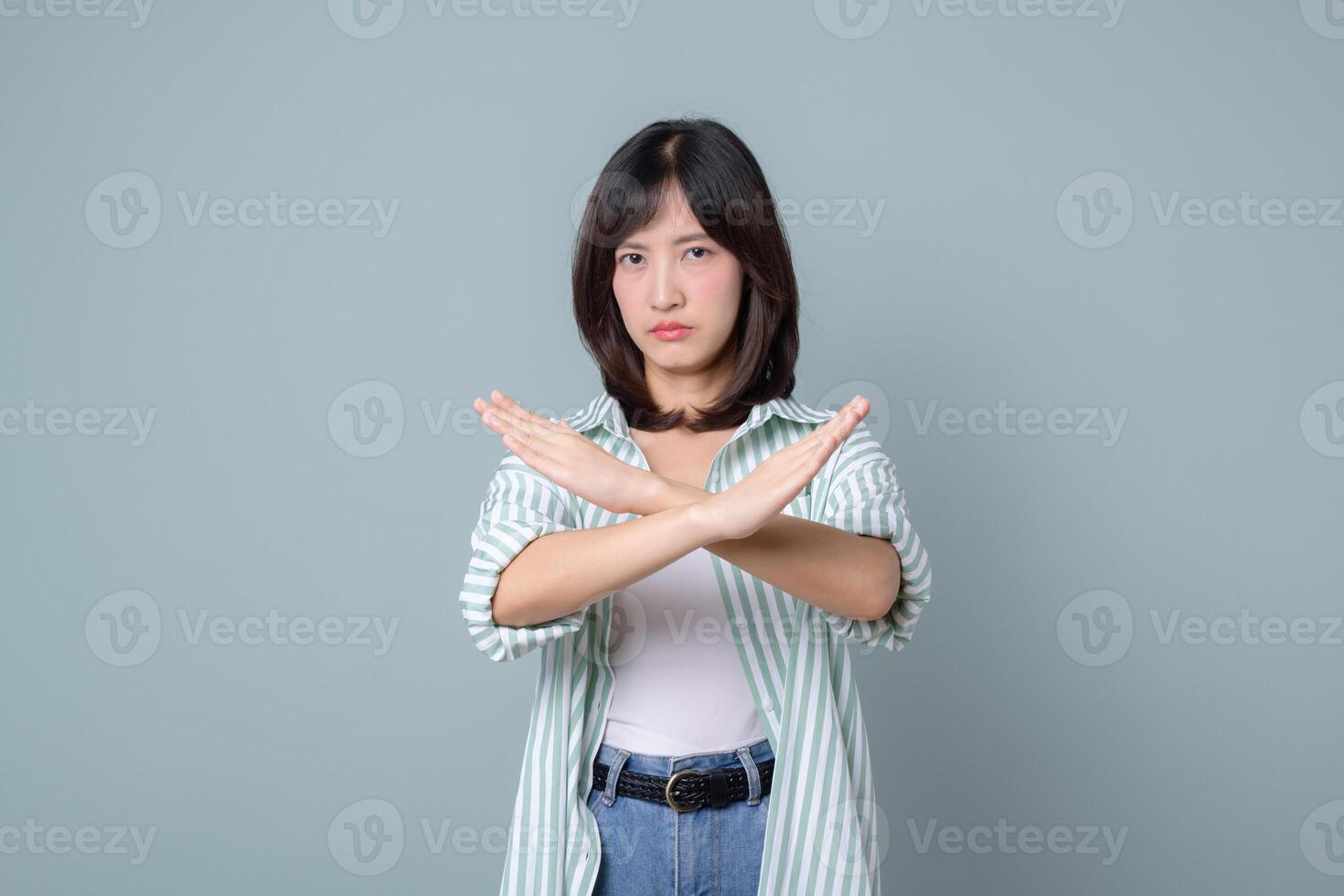 Southeast asian woman showing stop gesture with crossed arms expressing refusal or disapproval in creative and confident way photo
