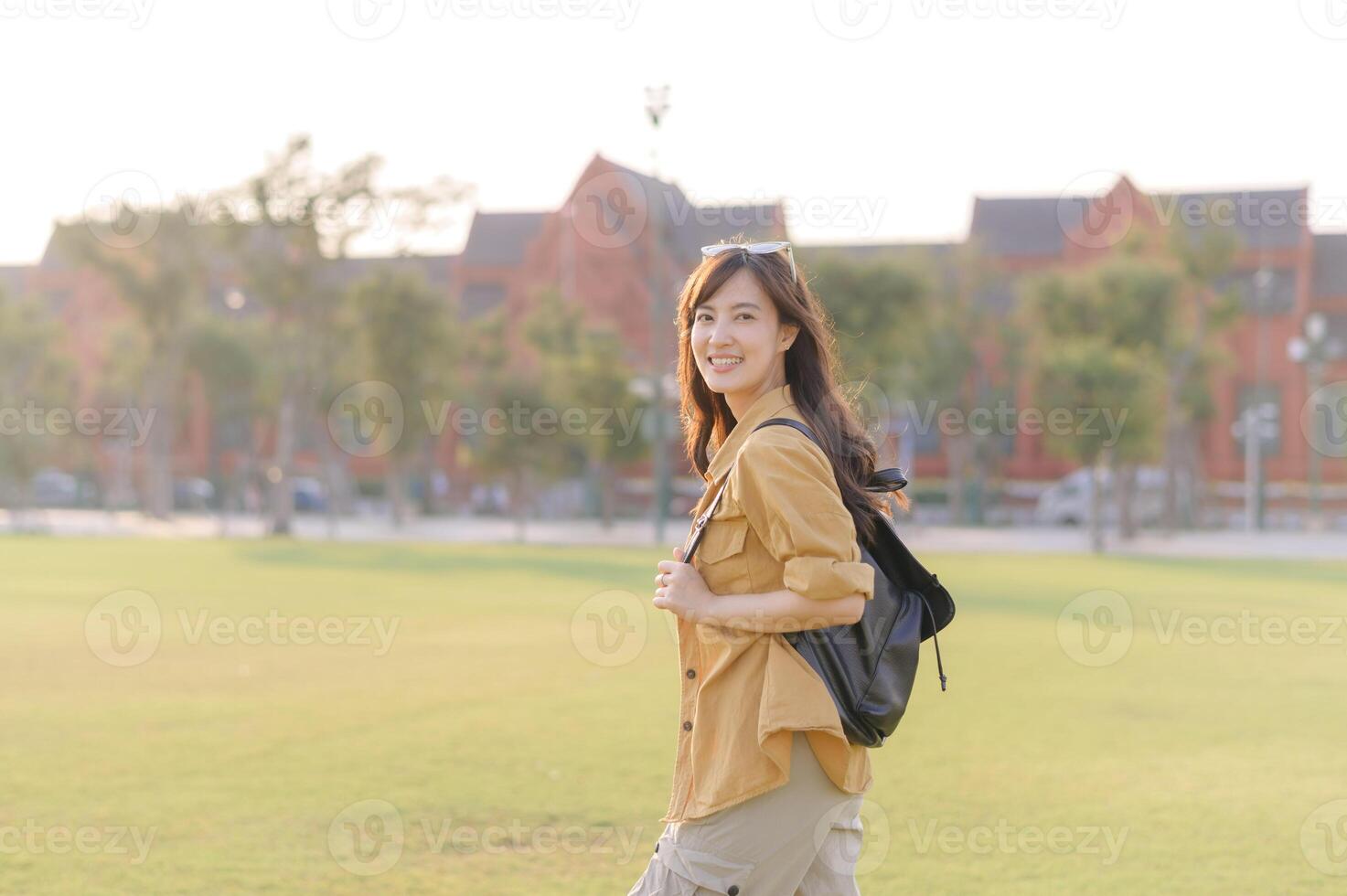 Southeast asian woman with backpack enjoys travel outdoors in sunny park setting with joyful expression capturing travel concept in casual outfit and natural light photo
