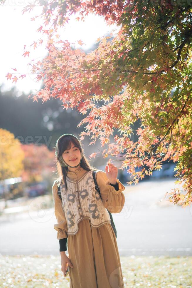 Southeast asian woman enjoys travel concept under colorful autumn leaves with soft sunlight creating warm and peaceful atmosphere in outdoor park setting photo