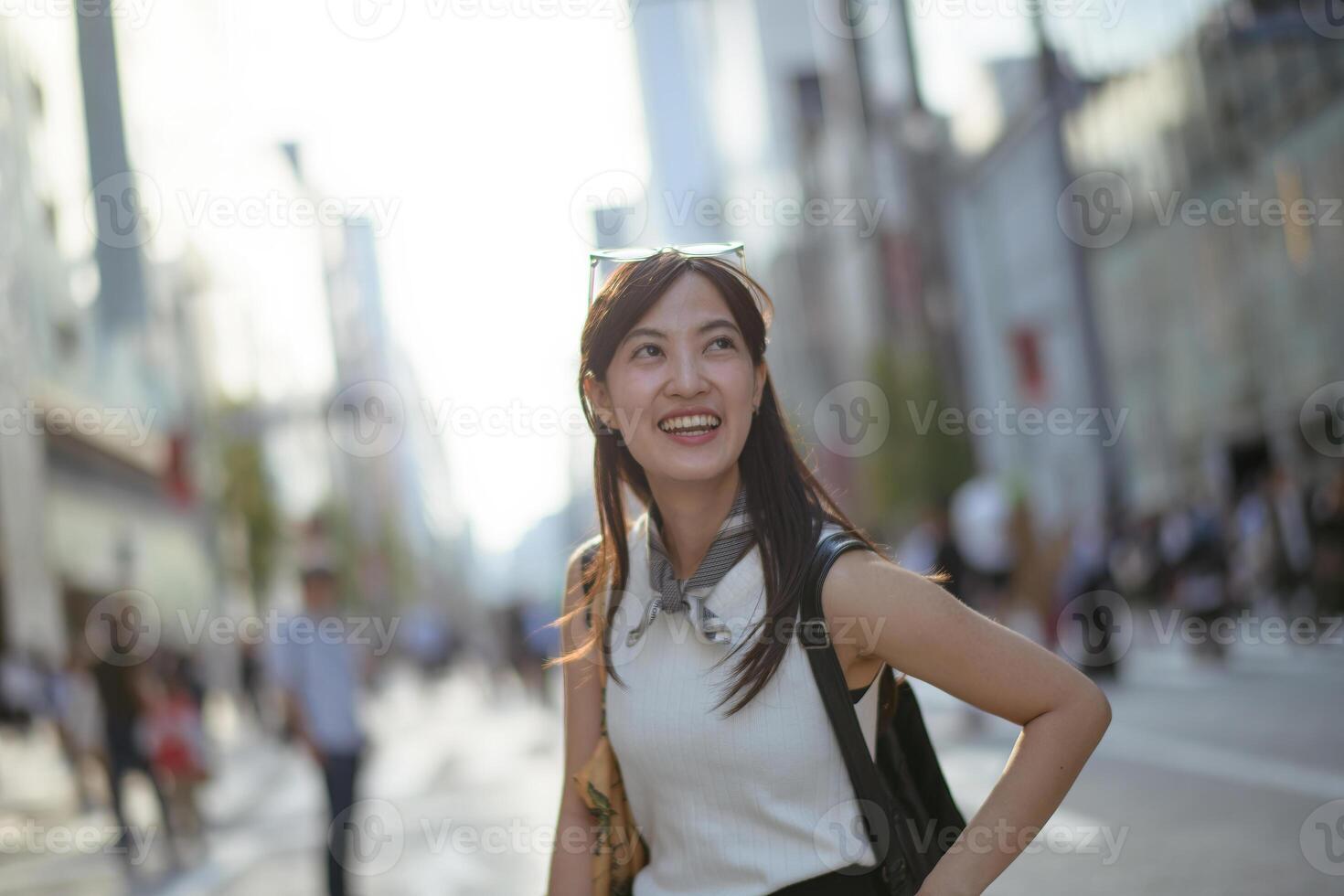 Southeast asian woman smiling happily on busy city street with sunlight and blurred background creating lively atmosphere photo