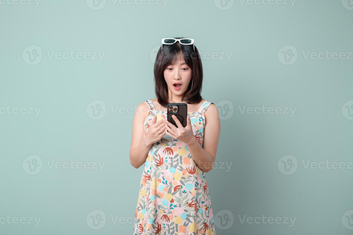 Southeast asian woman using mobile phone with surprised expression enjoying internet application on pastel background photo