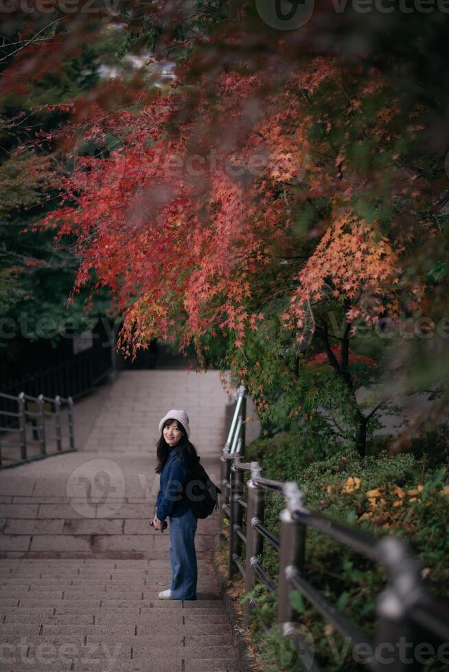 Southeast asian woman enjoys travel concept walking on stone stairs under colorful autumn leaves feeling peaceful and connected with nature in serene outdoor setting photo