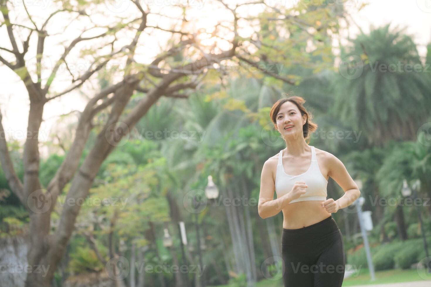 Southeast asian woman enjoying wellness and healthy lifestyle concept while doing exercise outdoors in park with joyful expression photo