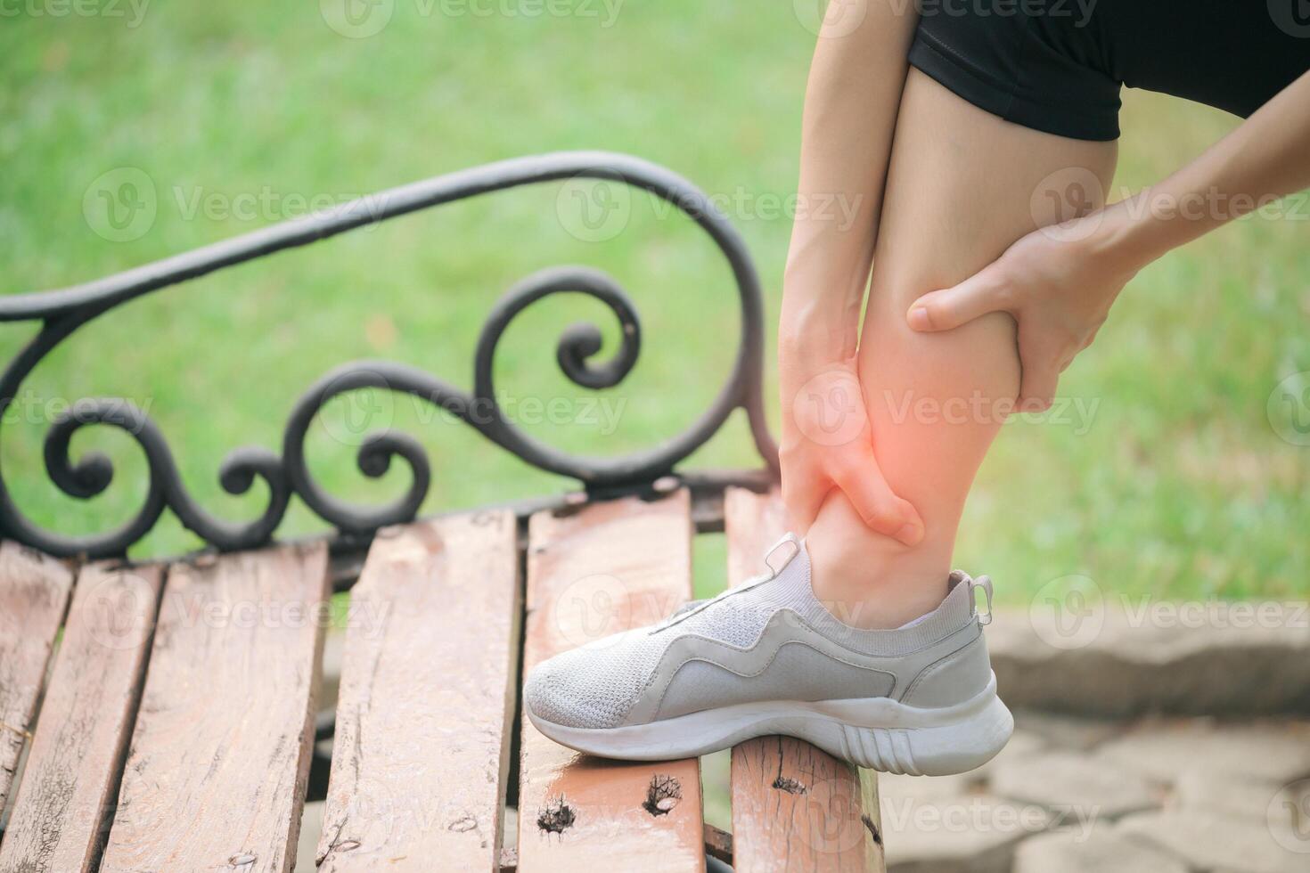 Southeast Asian woman wellness healthy lifestyle concept exercise injury pain outdoor park bench fitness shoe leg care photo
