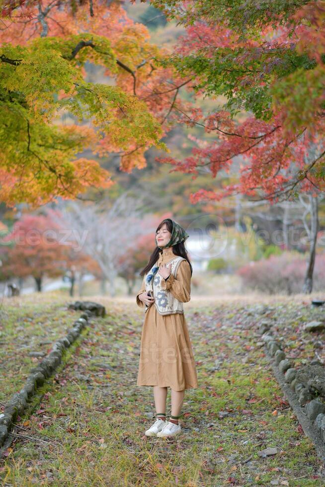 Southeast asian woman enjoys travel concept in autumn park surrounded by colorful leaves and peaceful nature creating serene and beautiful moment of calm and joy photo