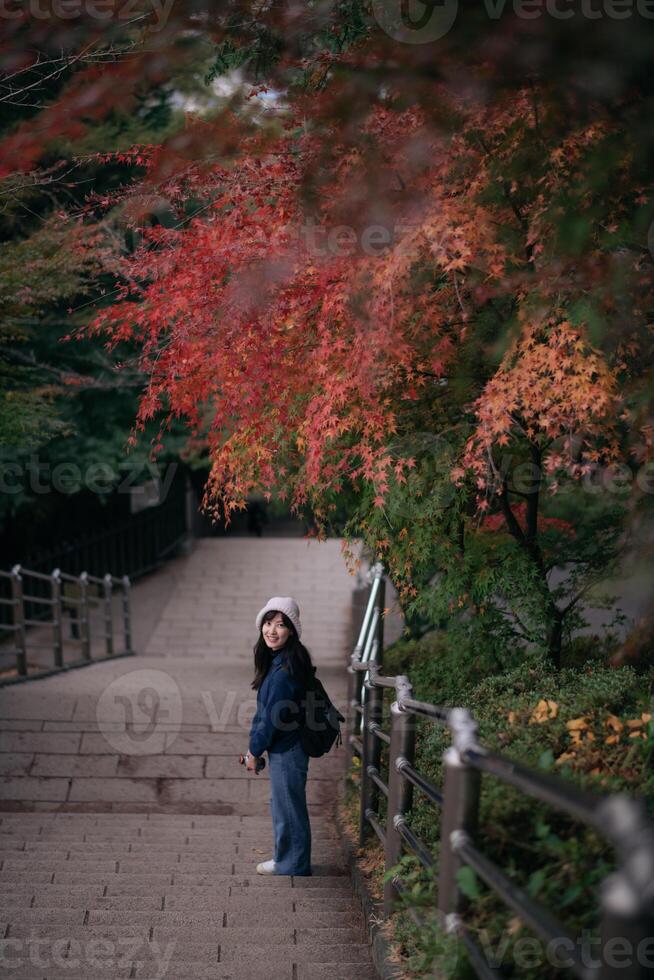 Southeast asian woman enjoys travel concept walking on stone stairs surrounded by colorful autumn leaves creating peaceful and joyful atmosphere in nature photo