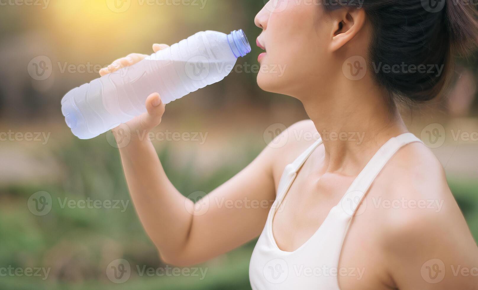 Southeast asian woman enjoying wellness and healthy lifestyle concept while exercising outdoors and drinking water for hydration and refreshment in natural environment photo