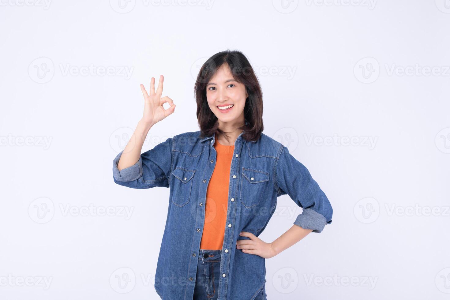 Southeast asian woman in casual denim clothing smiles confidently while making okay gesture for advertising or positive promotion photo