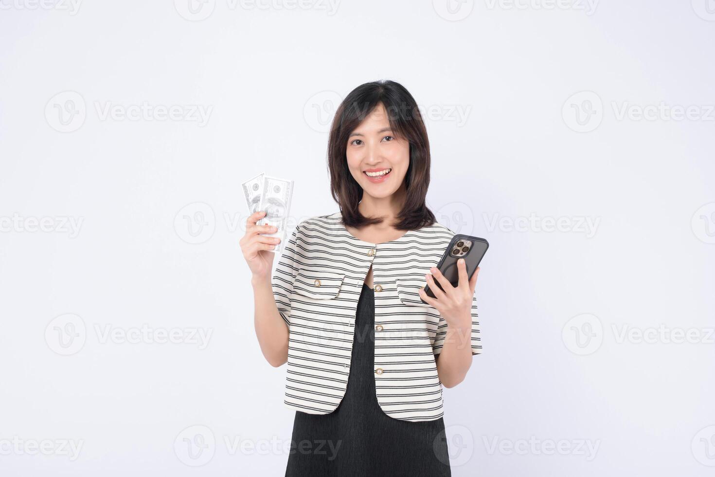 Southeast asian woman happily uses mobile phone application on internet while holding cash in her hand showing excitement and confidence in digital finance photo