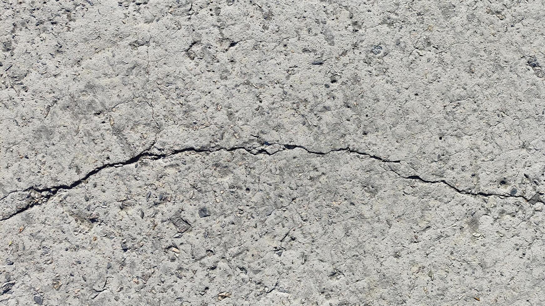 cracked gray concrete texture, a natural porous background with a prominent fissure for design and wallpaper use photo