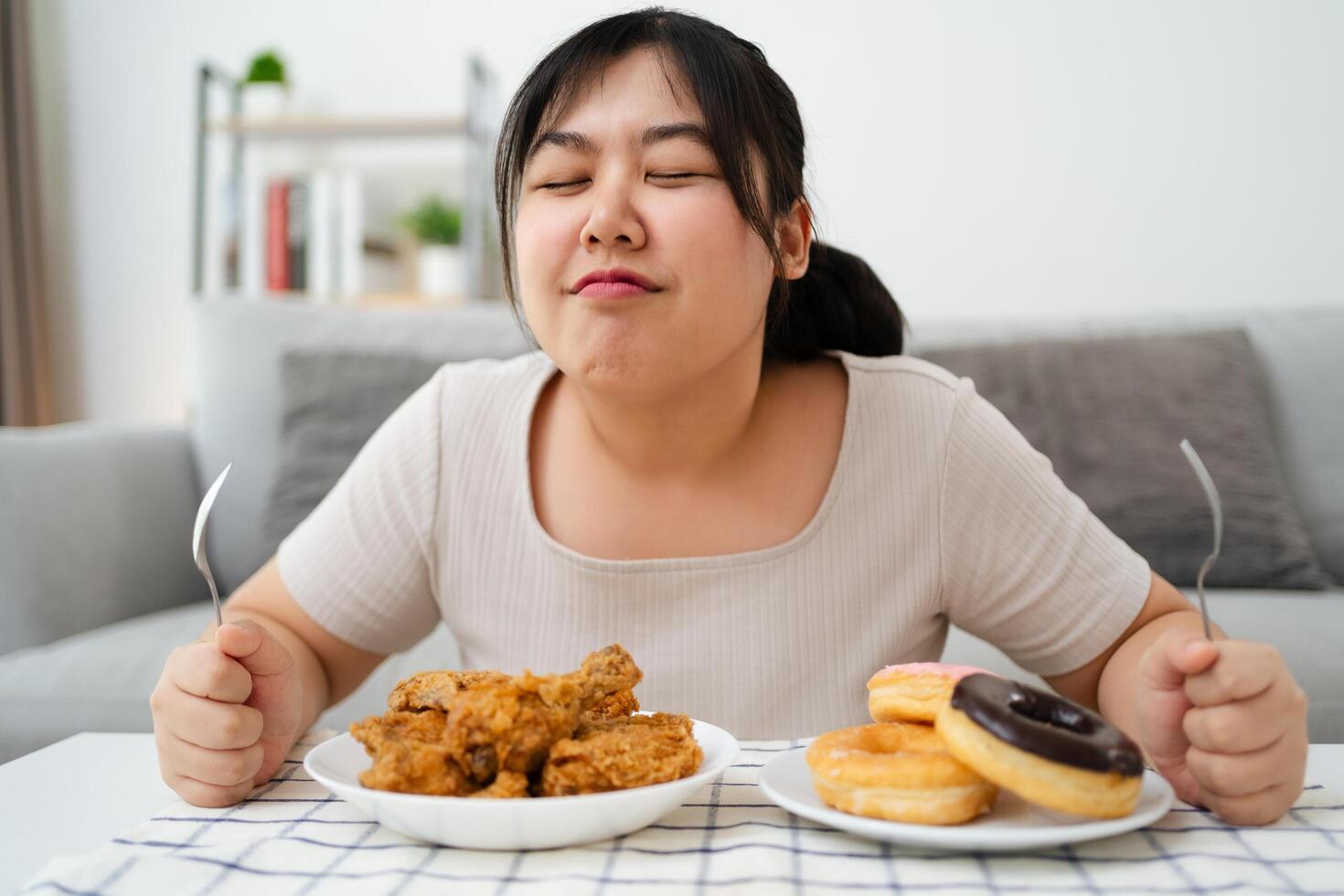 Asian girl is happy to eat her favorite food fried chicken and donuts, unhealthy food photo