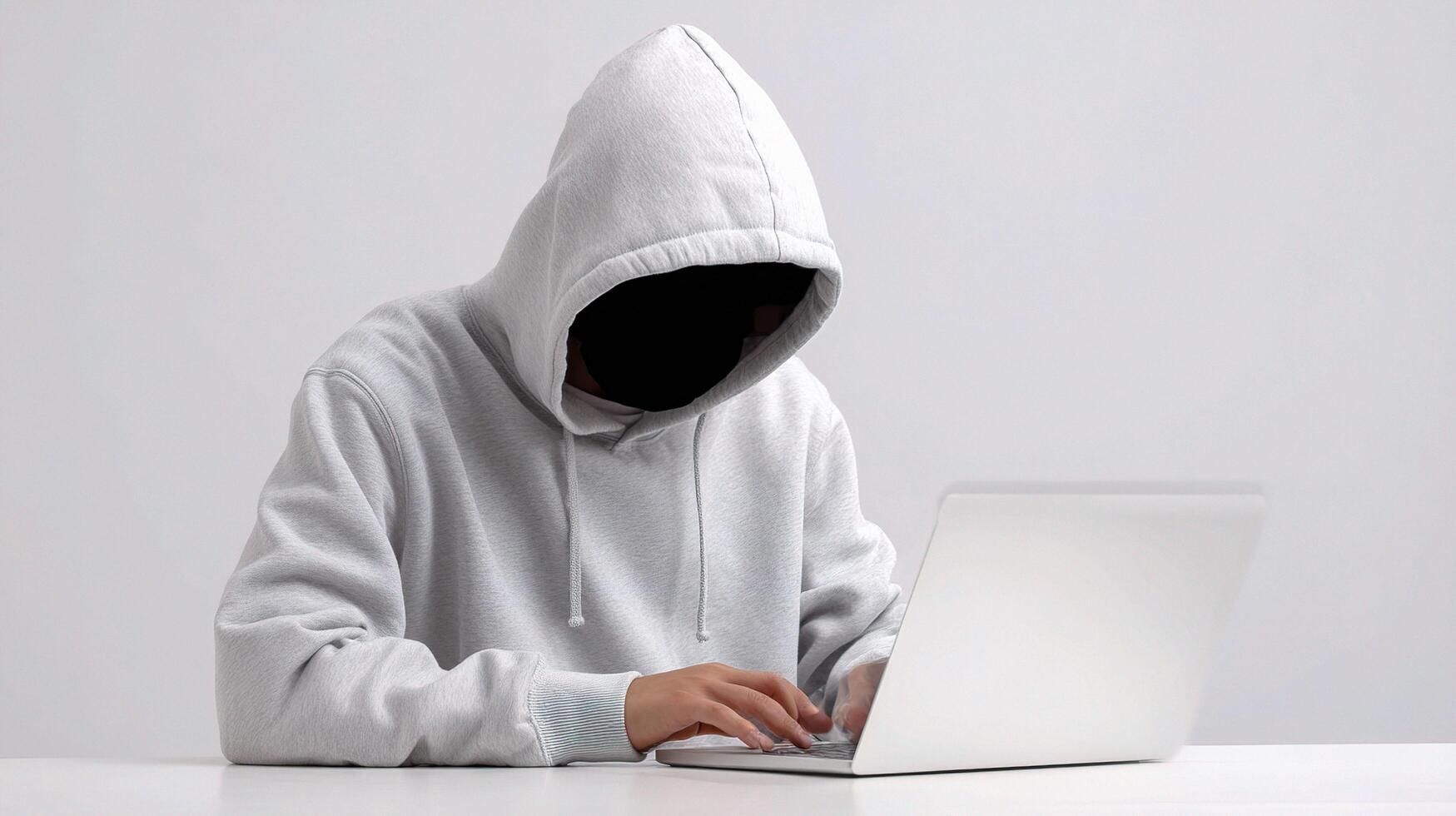 A person wearing a hoodie and using a laptop photo