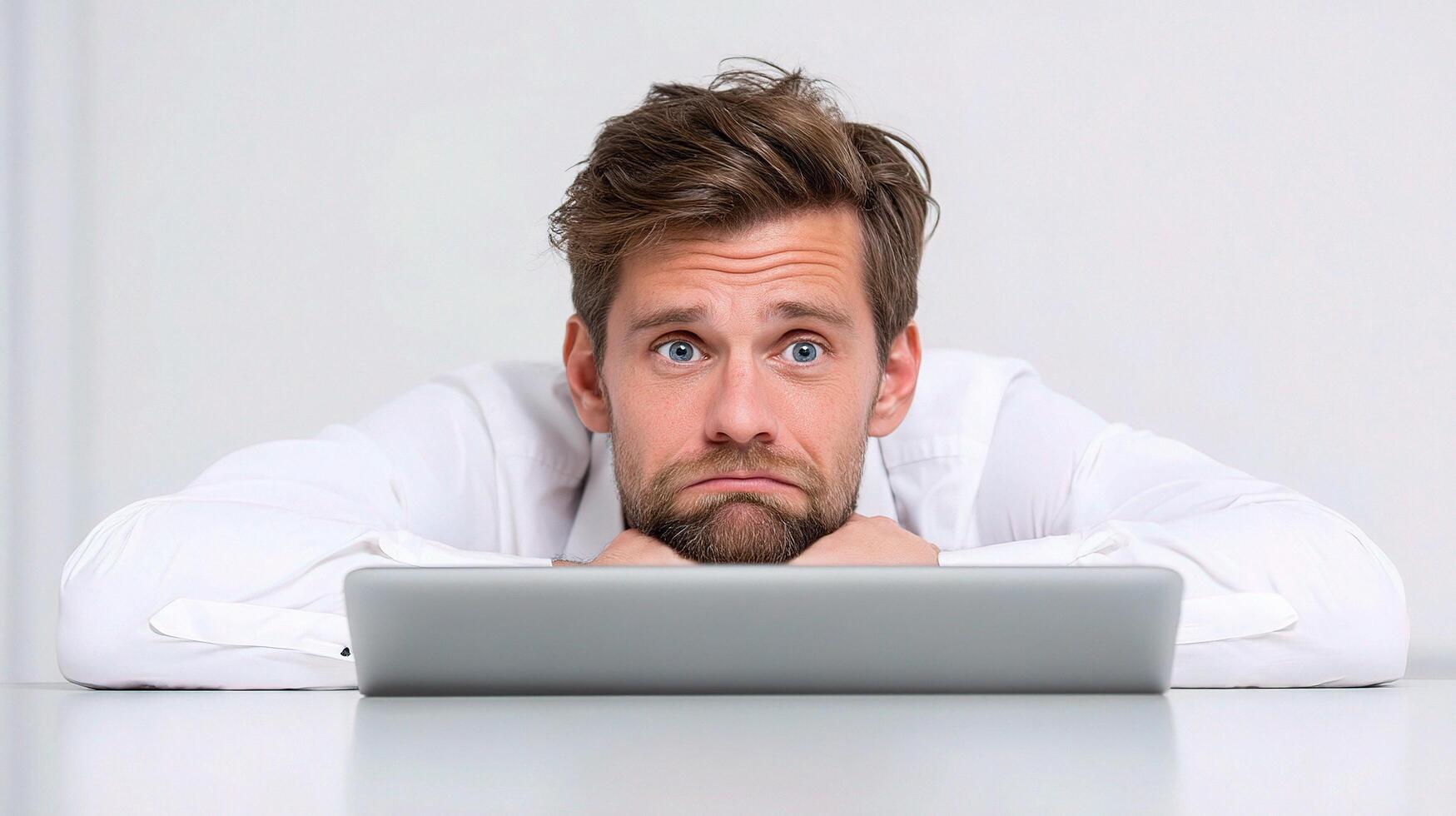 A man is looking at a laptop while sitting on a table photo