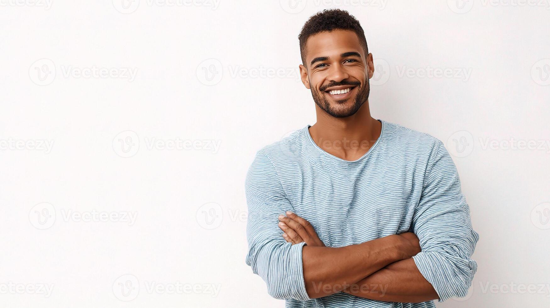 A man is smiling and standing in front of a white wall photo