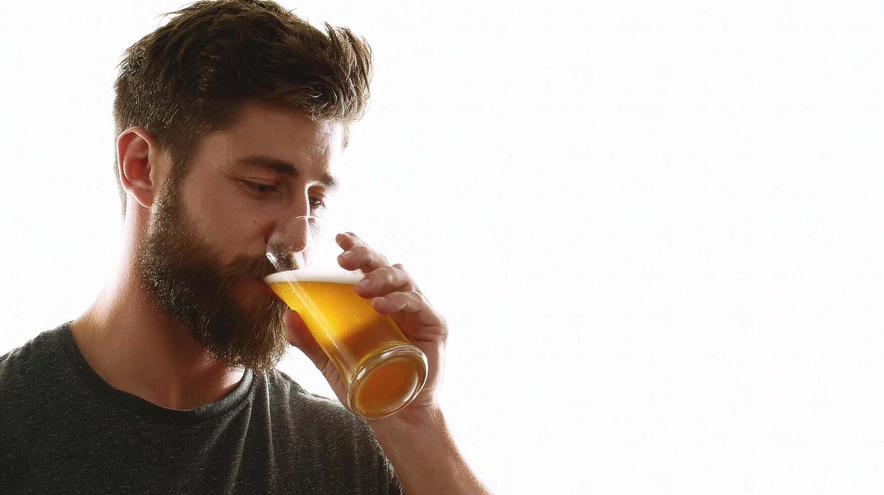 A man with a beard drinking from a glass of beer photo