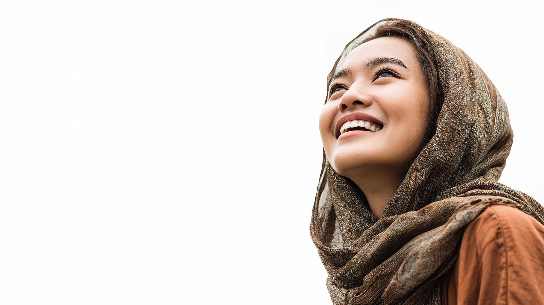 A woman wearing a scarf smiles up at the sky photo