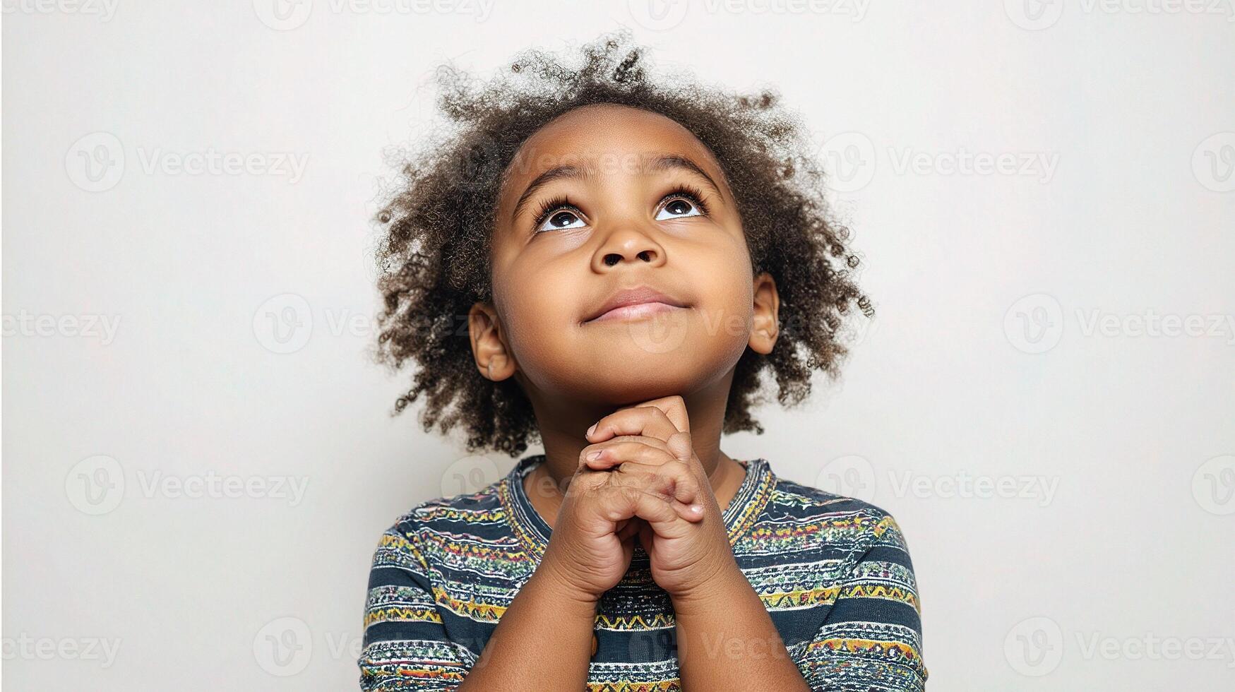 A young child is looking up with his hands on his chin photo