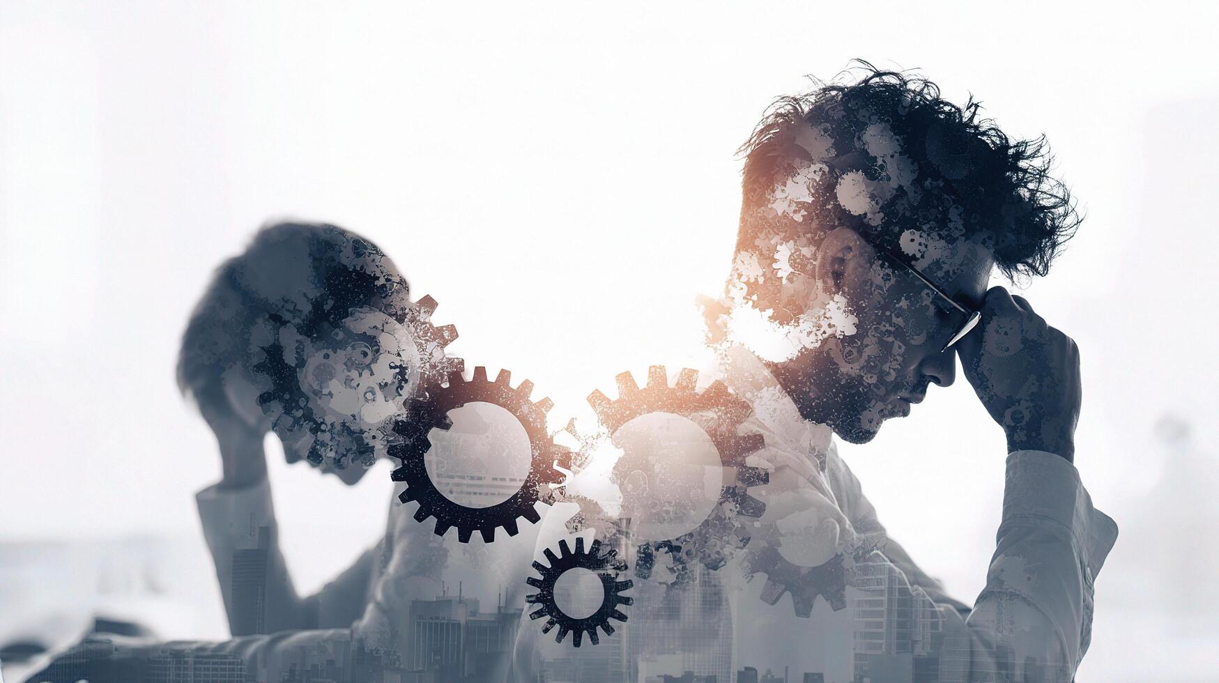 Two people are sitting at a desk with gears on their heads photo