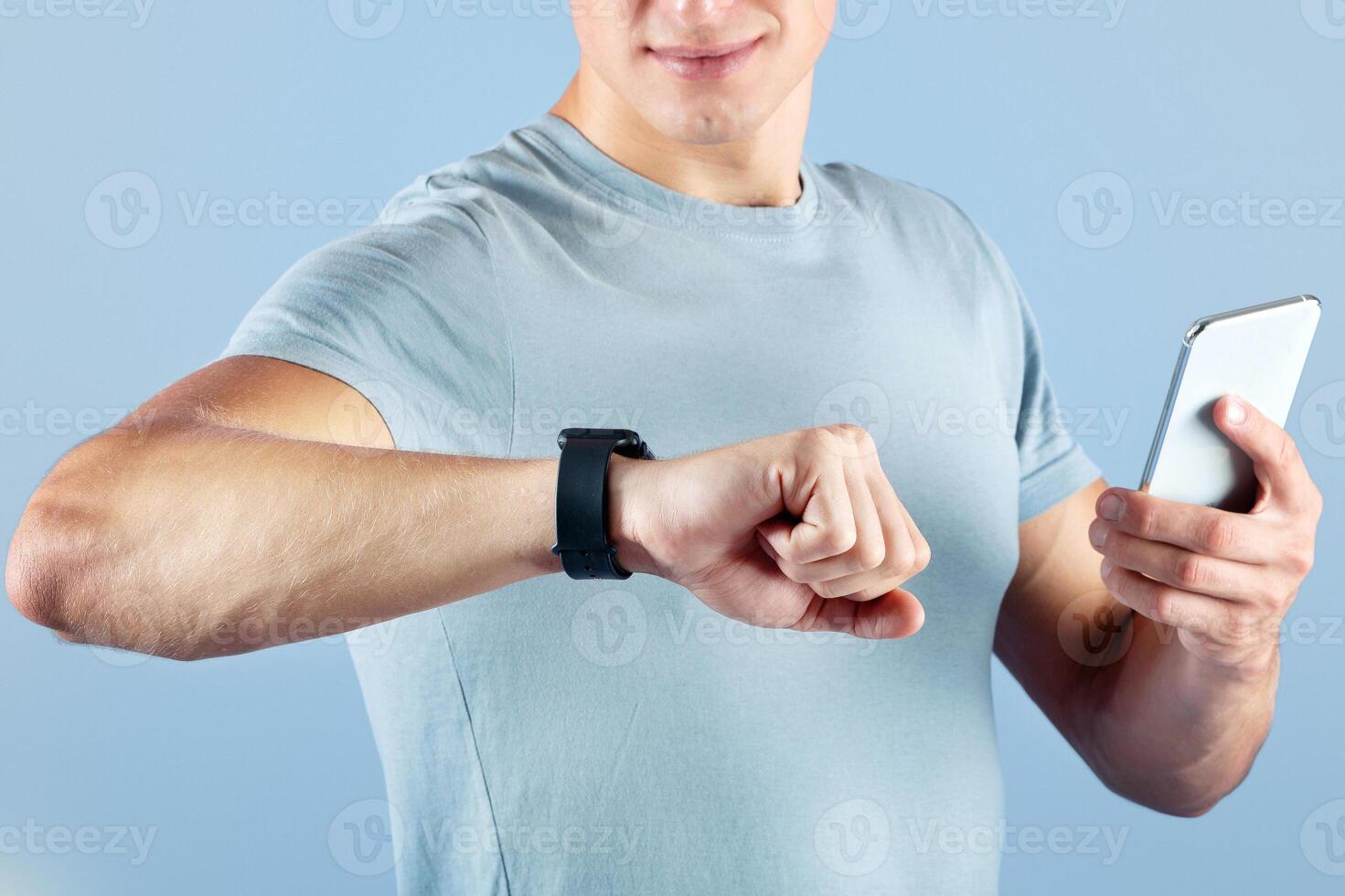 Cropped view of young sportsman with smartwatch and mobile phone over violet studio background, close up of hands. Millennial athlete checking his fitness tracker data during workout photo