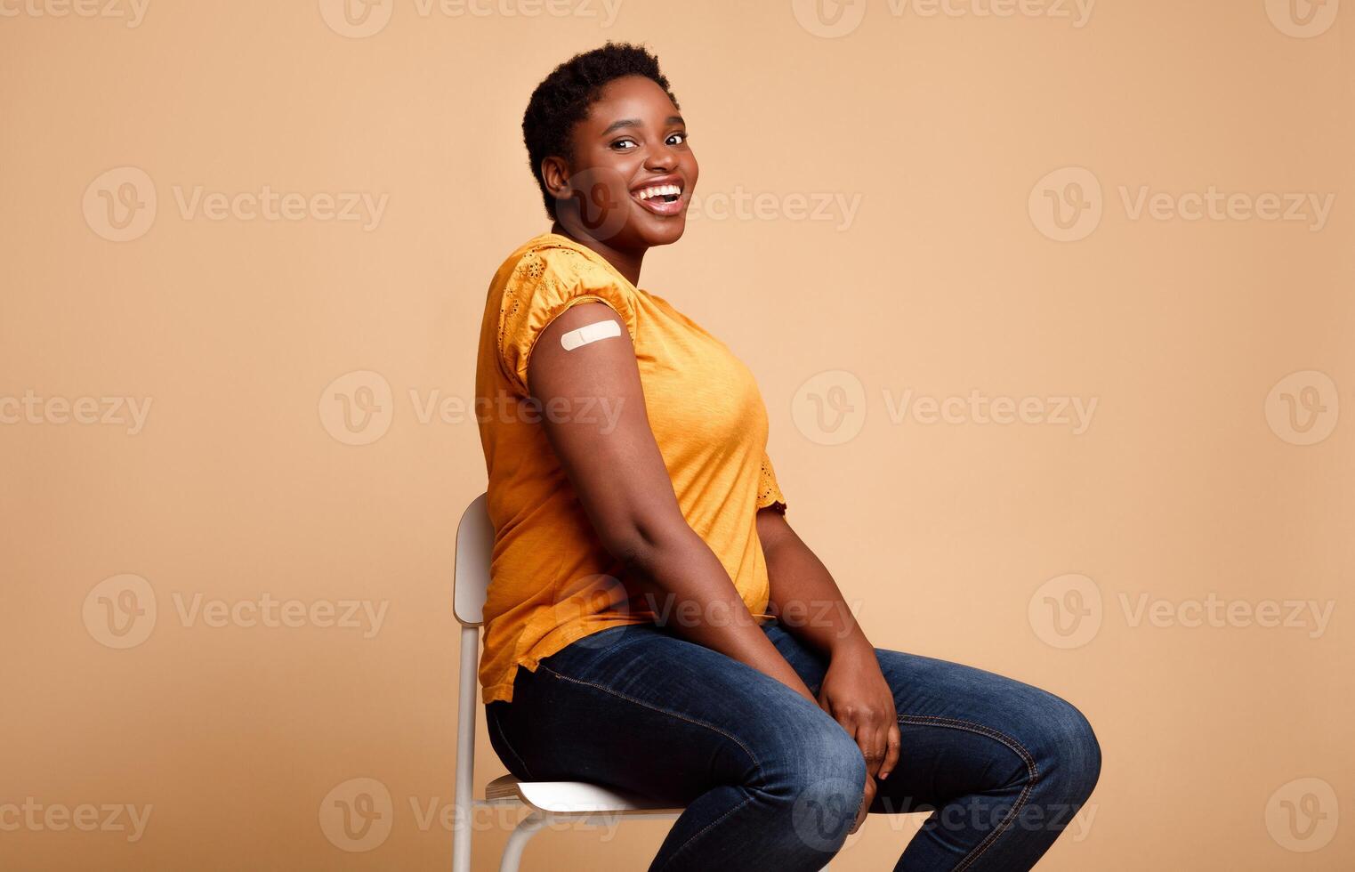 I Got My Covid-19 Vaccine. Happy Black Female Showing Vaccinated Arm After Antiviral Injection For Coronavirus Protection, Posing On Beige Background, Smiling To Camera. Corona Virus Vaccination photo