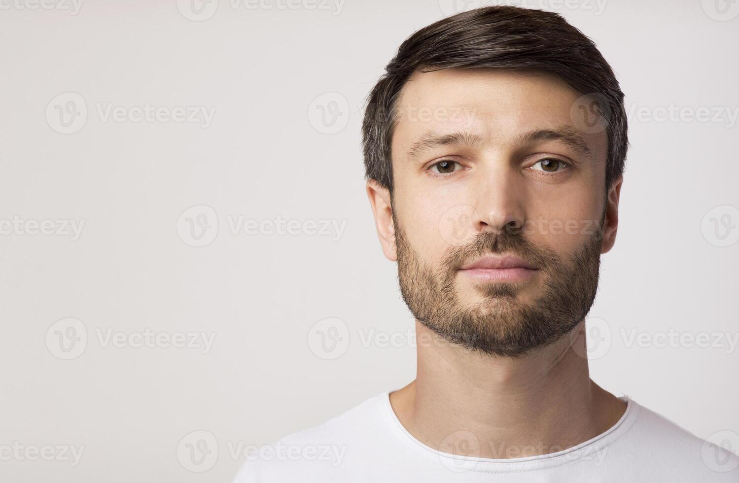 Portrait Of Confident Man Looking At Camera Posing Over White Studio Background. Copy Space photo