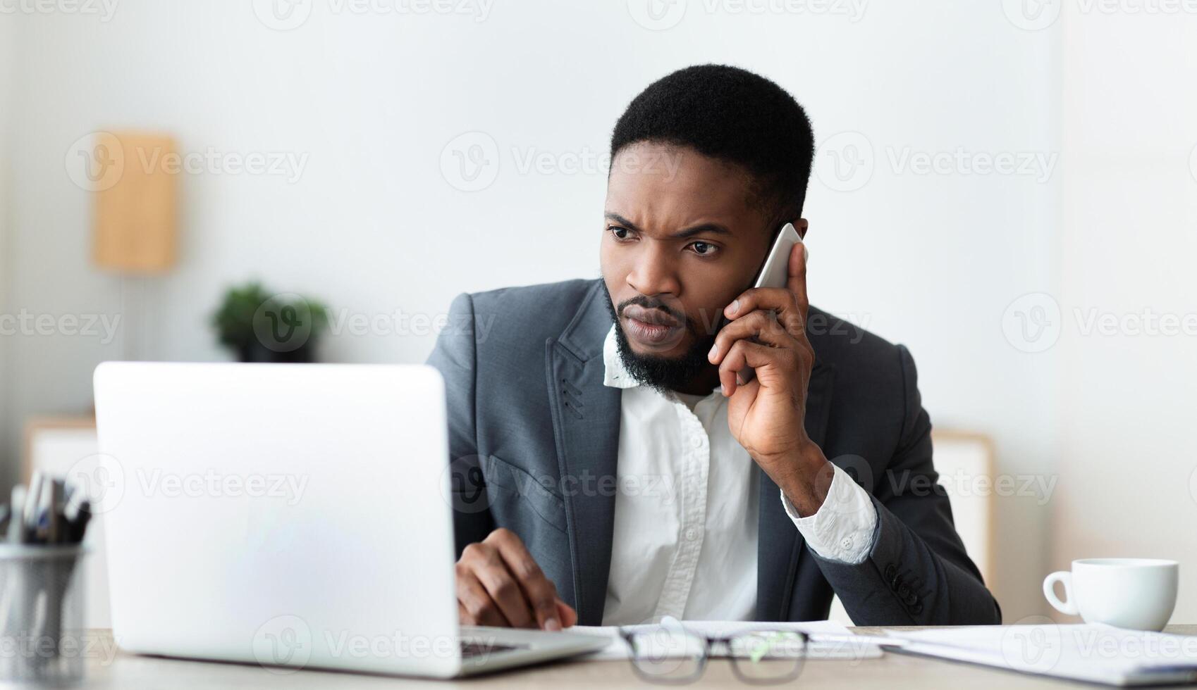 Concerned businessman talking on cell phone and looking at laptop screen, trying to reach technical support to solve issue with his computer, panorama photo