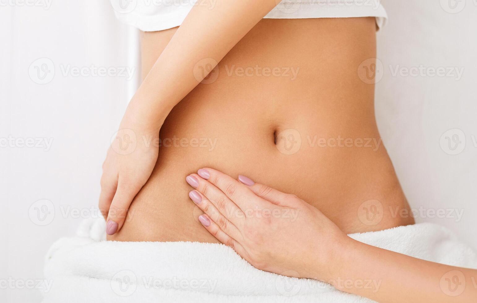 Healthcare concept. Young woman having stomach massage in spa center, top view photo