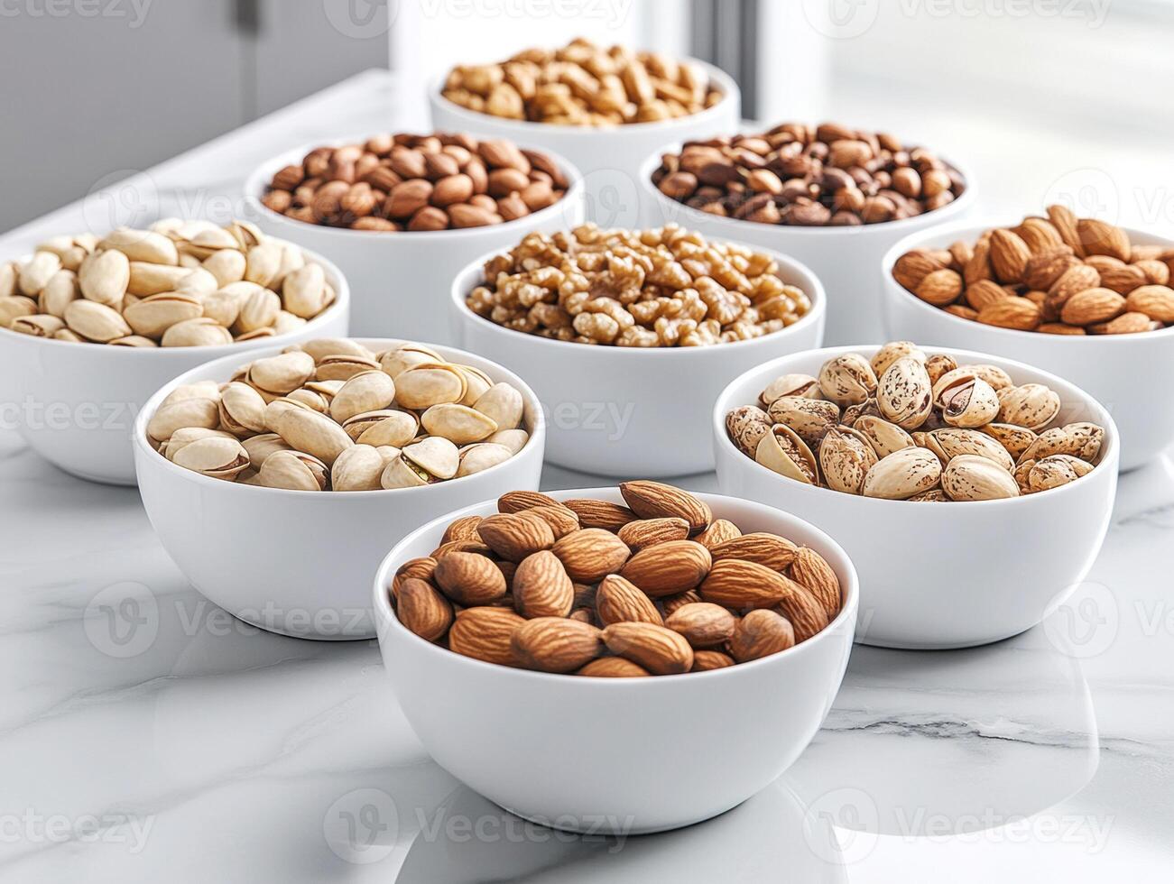 Variety of nuts displayed in elegant bowls on a marble countertop photo