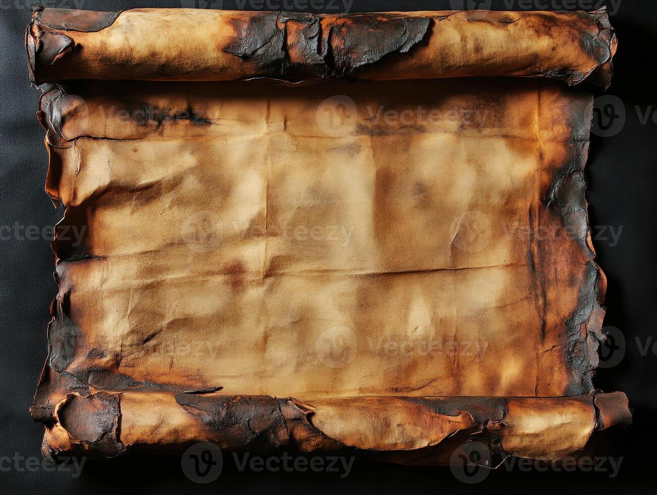 Ancient scroll with burned edges rests on black background photo