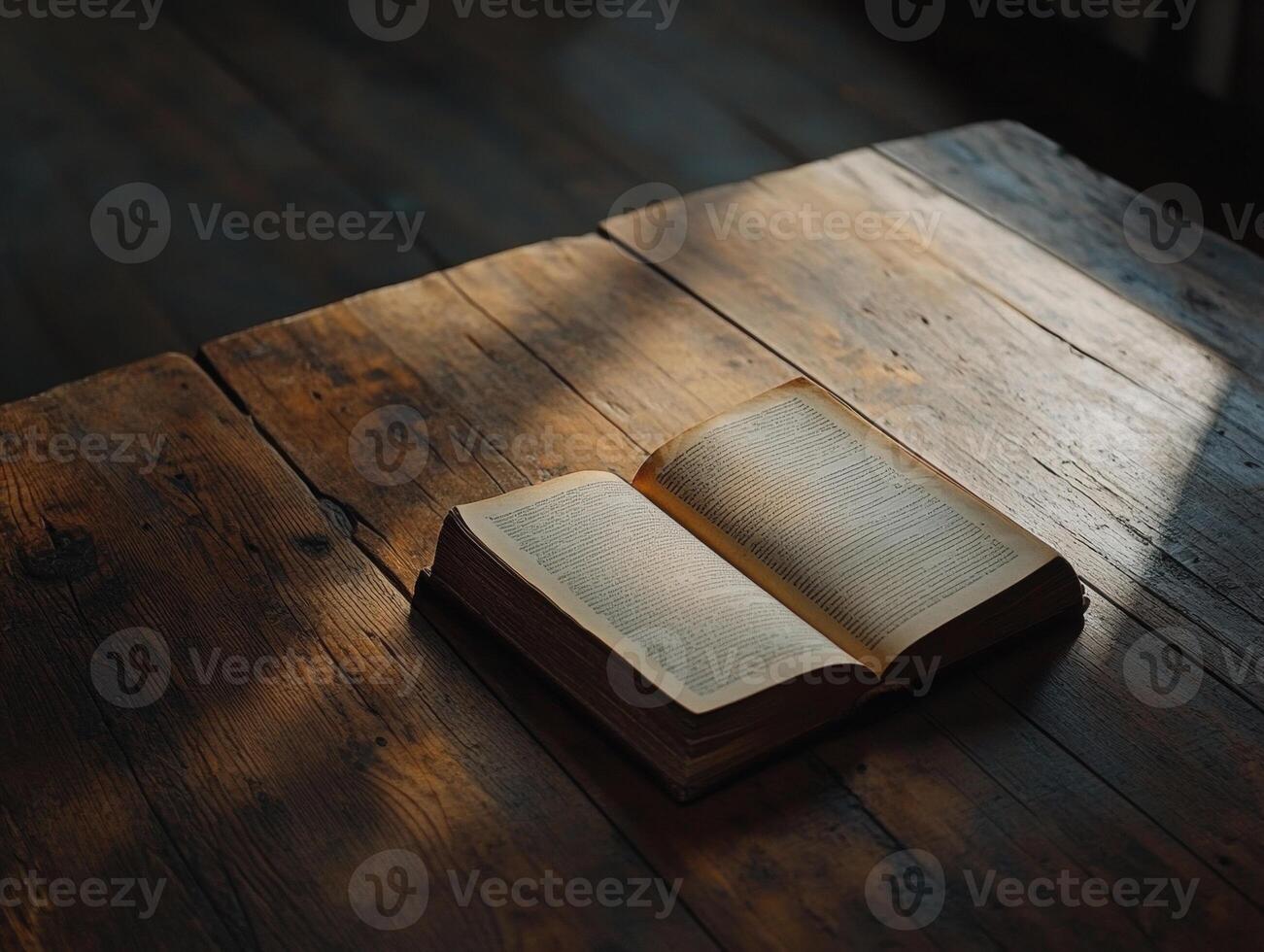 Open book on a wooden table with soft light illuminating pages photo