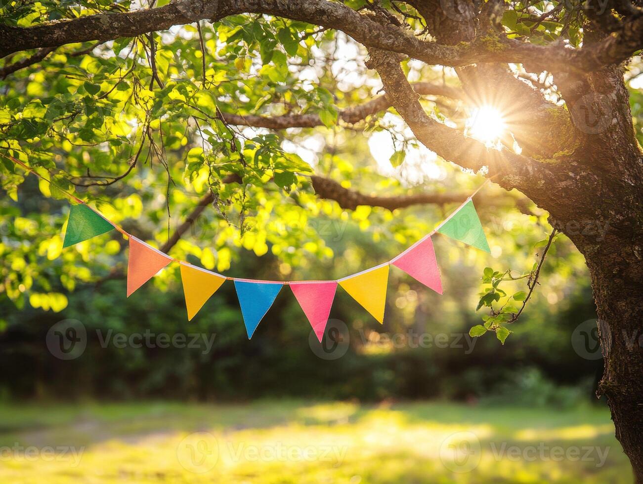 Colorful bunting flags hang from tree branches in warm sunlight photo