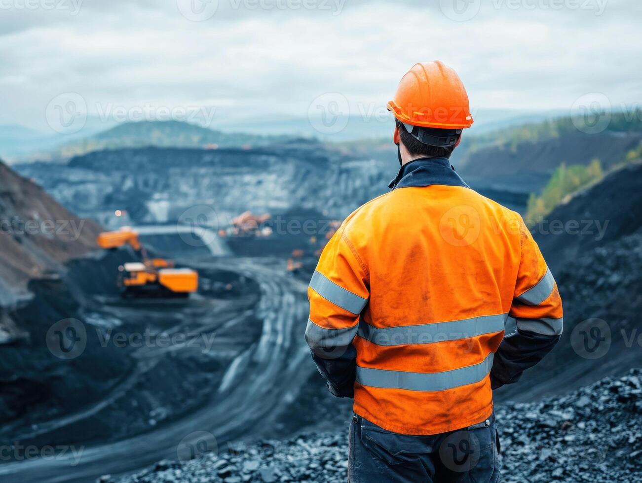 Worker surveys active mining site with machinery in operation photo