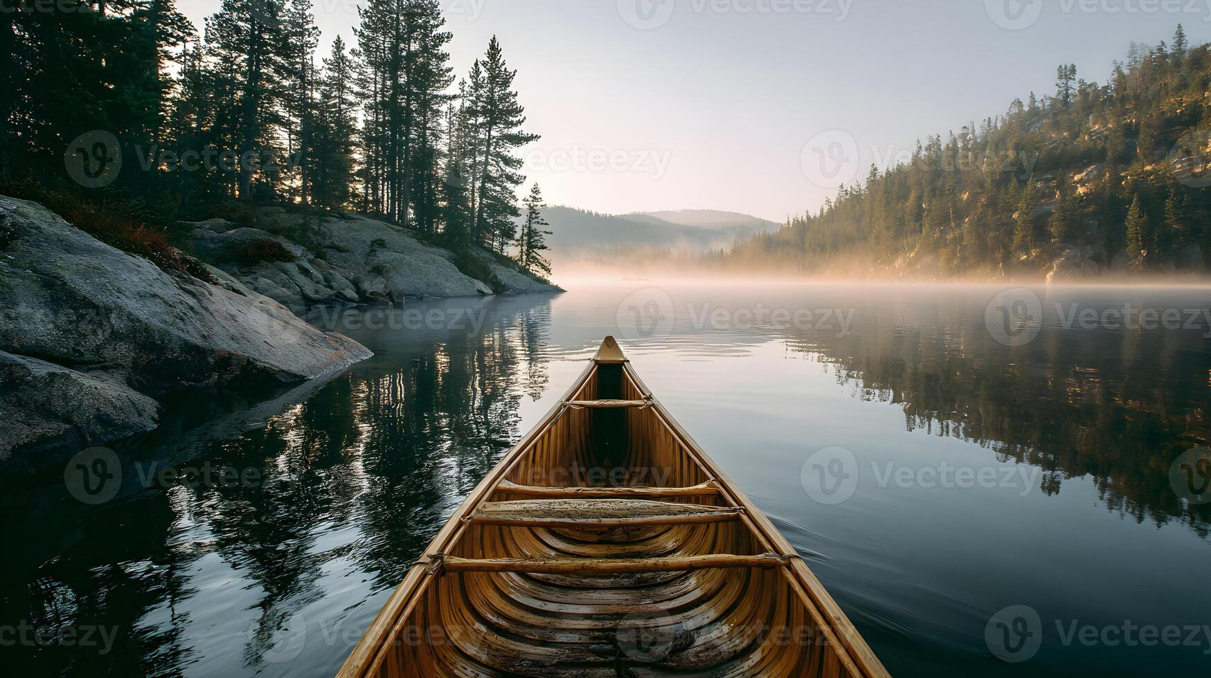 Wooden canoe floats on a tranquil lake surrounded by misty mountains and lush trees photo