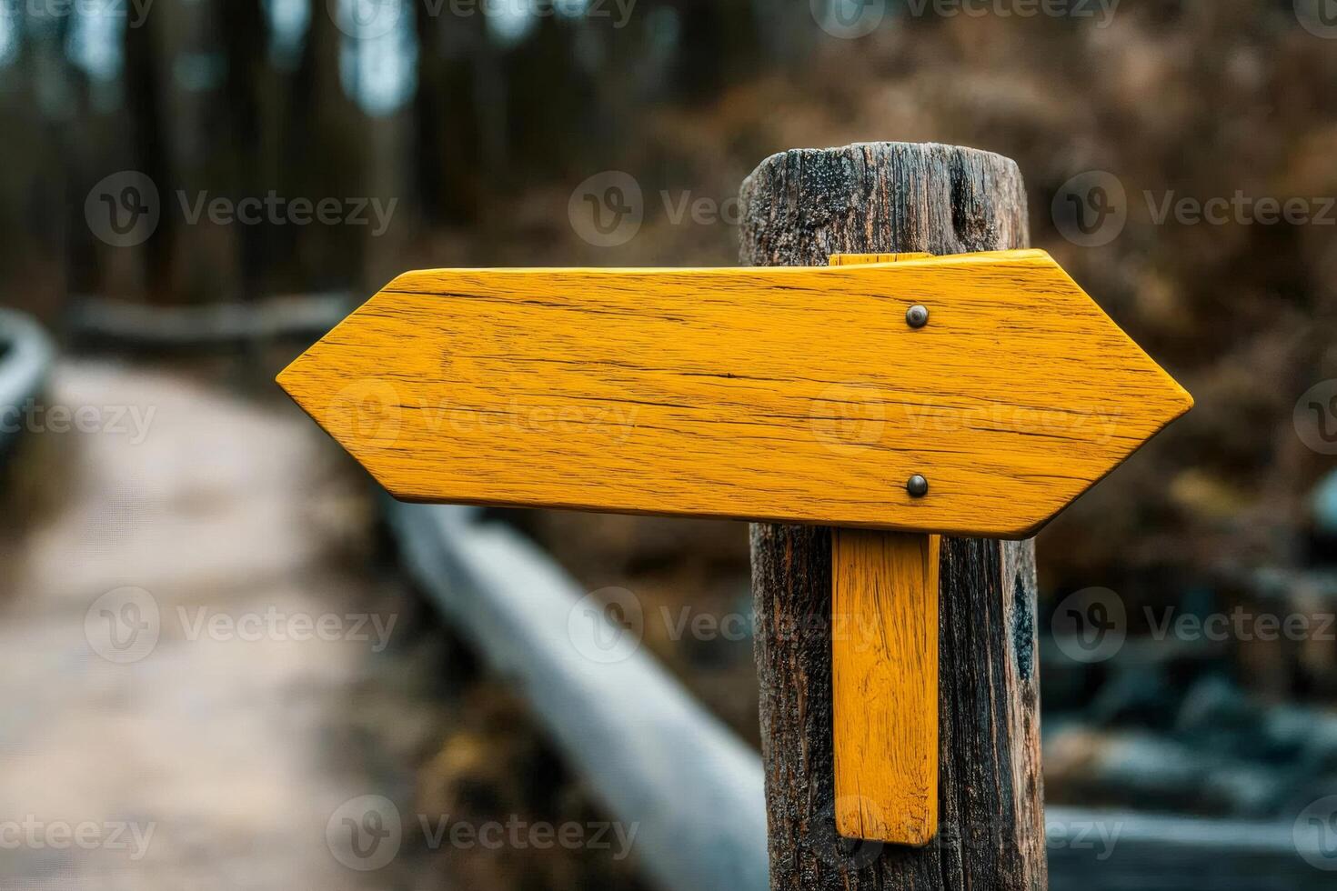 Yellow wooden arrow sign pointing to the left in a forest path photo