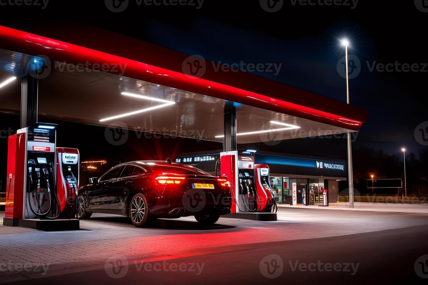 Black car refueling at empty gas station at night photo