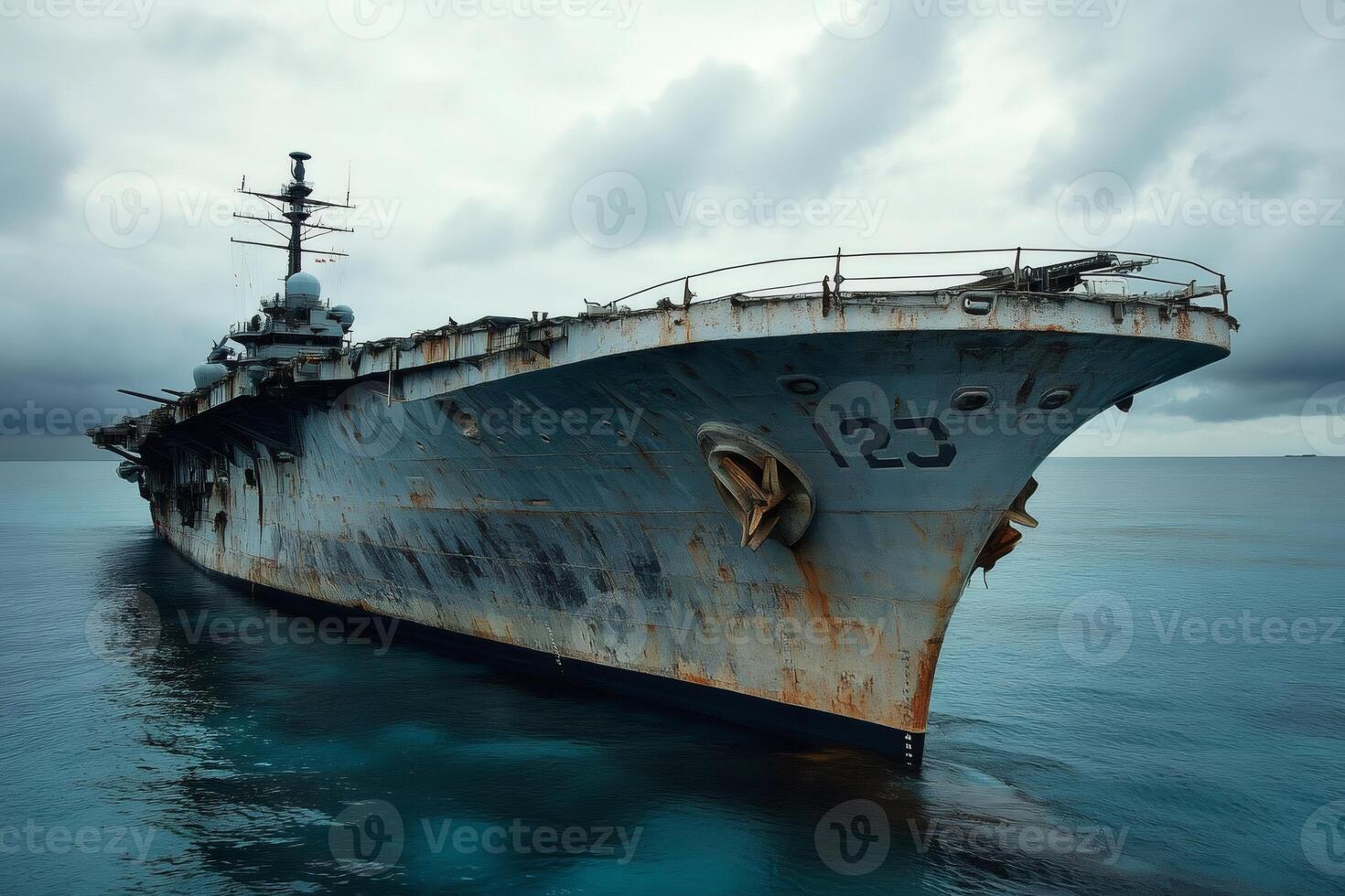 Abandoned aircraft carrier rusting in the ocean under a cloudy sky photo