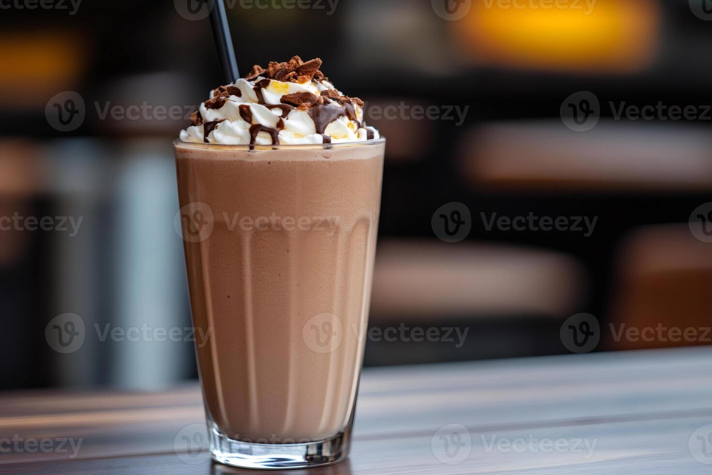 Chocolate milkshake with whipped cream and chocolate chips topping is standing on a table photo